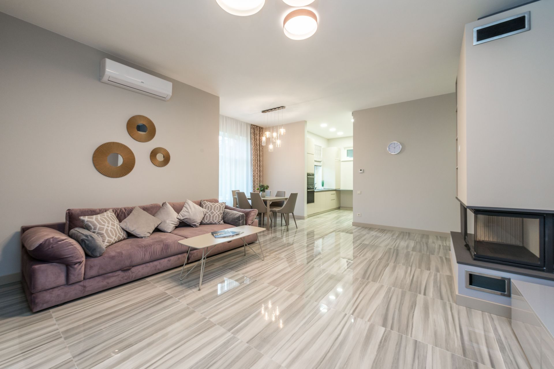 Large contemporary flat with cozy large sofa in front of electric fireplace and table with chair in dining room